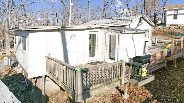 rear view of house featuring a wooden deck and metal roof