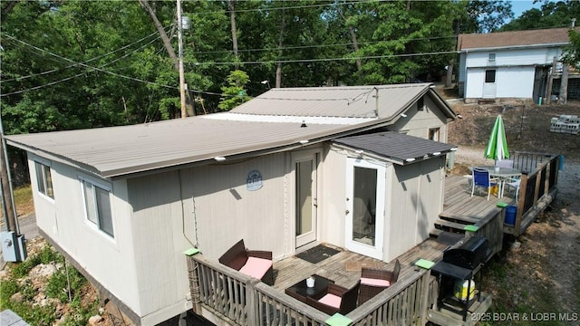 back of property with metal roof, an outbuilding, outdoor dining area, and a deck