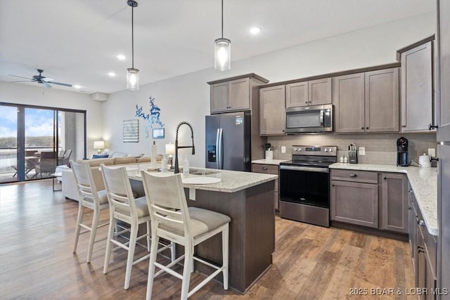 1065 Topsider Ln Unit 508, Osage Beach, MO 65065 - kitchen featuring stainless steel appliances, open floor plan, backsplash, a ceiling fan, and wood finished floors