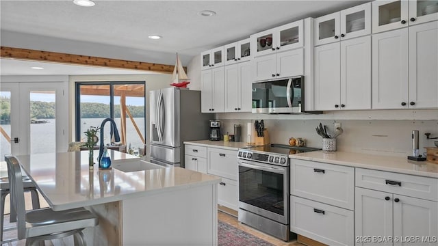 342 Porter Mill Springs Dr, Sunrise Beach, MO 65079 - kitchen with white cabinets, a sink, stainless steel appliances, and a breakfast bar area