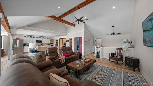 342 Porter Mill Springs Dr, Sunrise Beach, MO 65079 - living area featuring high vaulted ceiling, a ceiling fan, light wood-type flooring, a wood stove, and beamed ceiling