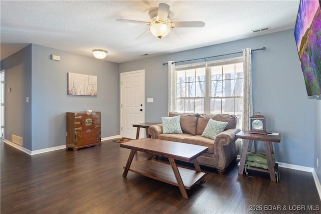 living room with a ceiling fan, a textured ceiling, baseboards, visible vents, and wood finished floors
