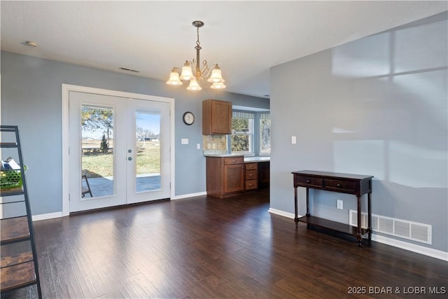 unfurnished dining area with french doors, visible vents, an inviting chandelier, dark wood-style floors, and plenty of natural light