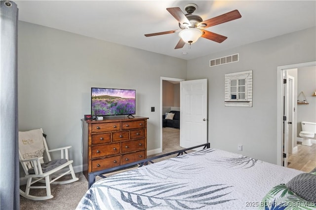 carpeted bedroom featuring baseboards, visible vents, a ceiling fan, and ensuite bath