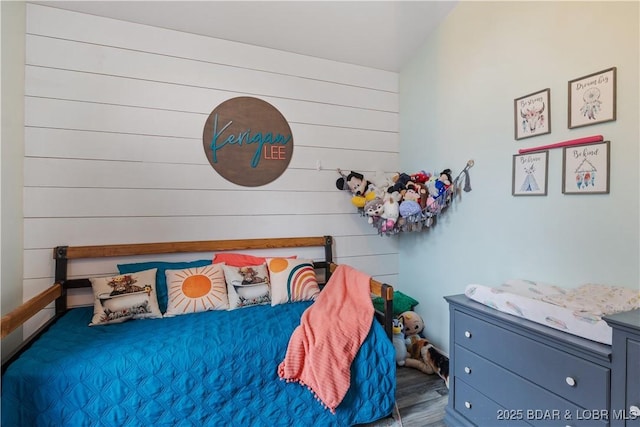 bedroom with wood walls and wood finished floors