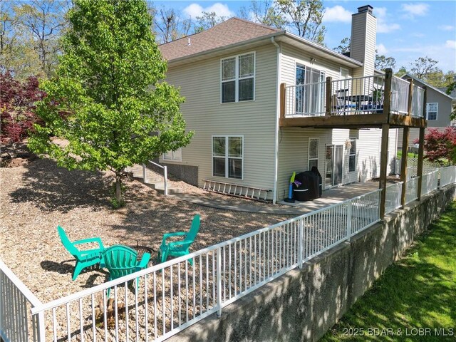 back of house with fence, a deck, a chimney, and a shingled roof