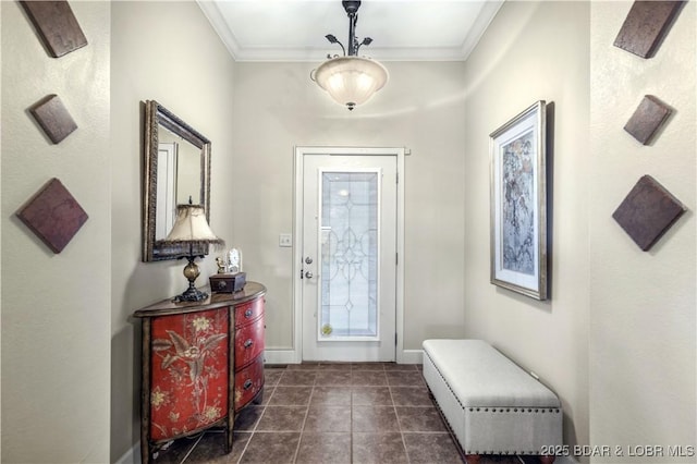 foyer entrance featuring dark tile patterned flooring, crown molding, and baseboards
