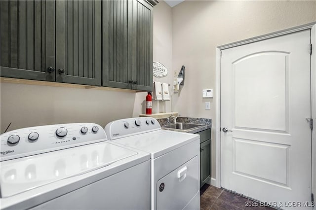 washroom featuring dark tile patterned floors, a sink, cabinet space, and independent washer and dryer