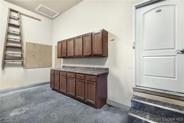 stairway featuring attic access, unfinished concrete flooring, and baseboards