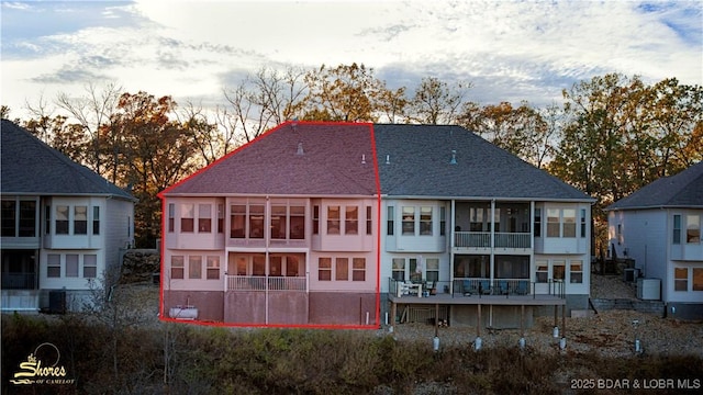 back of house featuring a sunroom and roof with shingles
