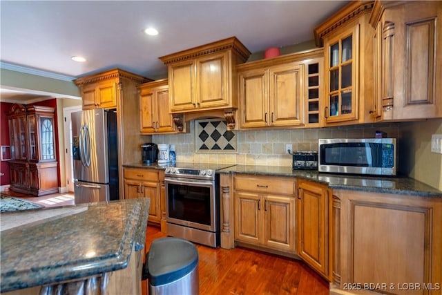 4956 Shorewood Dr, Osage Beach, MO 65065 - kitchen with glass insert cabinets, brown cabinetry, stainless steel appliances, and dark stone counters