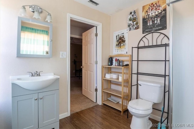 bathroom with toilet, visible vents, vanity, and wood finished floors