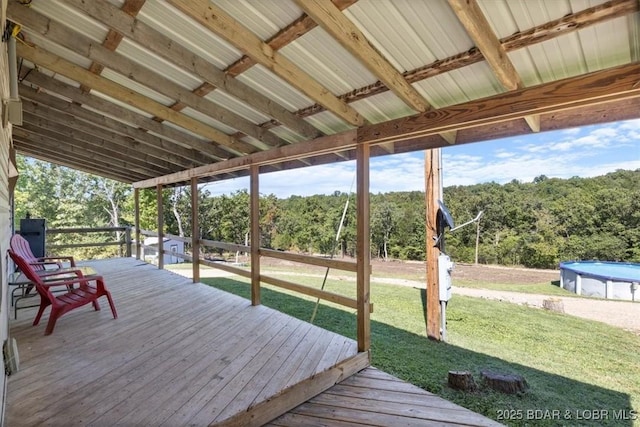 deck with an outdoor pool, a forest view, and a lawn