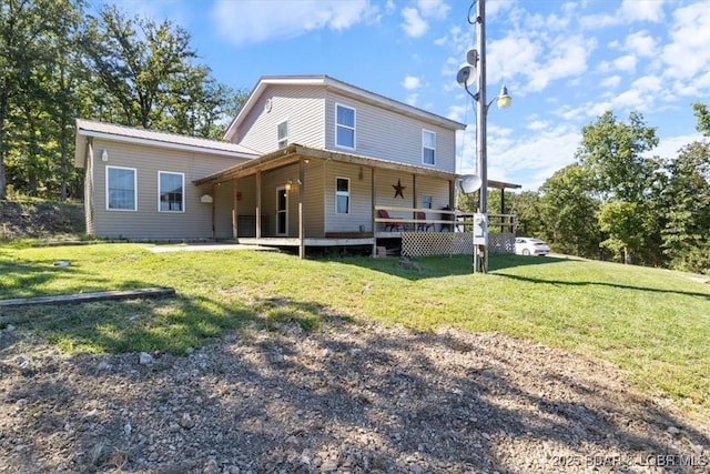 rear view of house featuring a lawn and metal roof