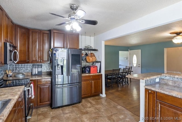 kitchen with a ceiling fan, a textured ceiling, appliances with stainless steel finishes, and decorative backsplash