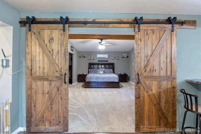 carpeted bedroom featuring a textured ceiling, a barn door, and baseboards