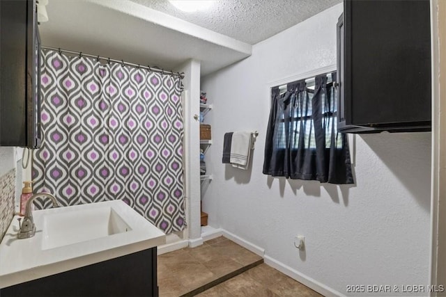 full bathroom with tile patterned floors, a shower with shower curtain, vanity, baseboards, and a textured ceiling
