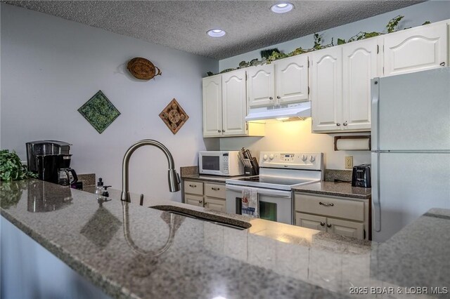 6570 Pelican Dr Unit 404, Osage Beach, MO 65065 - kitchen featuring white appliances, under cabinet range hood, dark stone counters, recessed lighting, and white cabinets