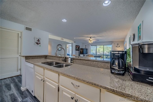 6570 Pelican Dr Unit 404, Osage Beach, MO 65065 - kitchen featuring white dishwasher, a sink, a textured ceiling, light stone countertops, and white cabinetry