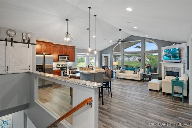 5177 Vicus Castry, Osage Beach, MO 65065 - kitchen with stainless steel appliances, brown cabinets, a kitchen breakfast bar, light stone counters, and open floor plan