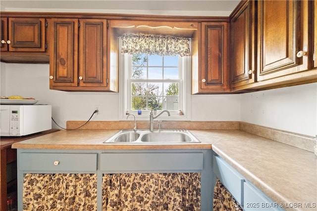 9 Gage Rd, Eldon, MO 65026 - kitchen with a sink, white microwave, brown cabinets, and light countertops