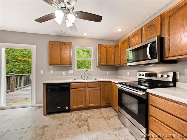 kitchen featuring a sink, brown cabinets, stainless steel appliances, ceiling fan, and light countertops