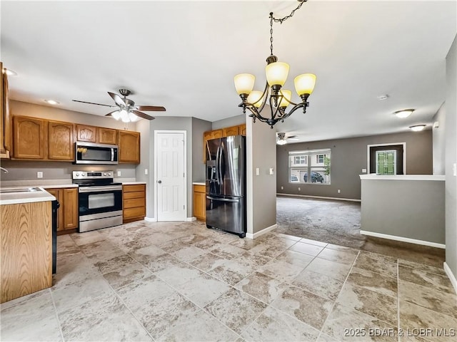 kitchen featuring baseboards, stainless steel appliances, ceiling fan with notable chandelier, and light countertops