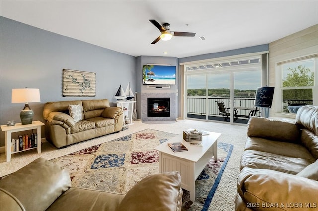 living room with ceiling fan, a healthy amount of sunlight, carpet floors, and a glass covered fireplace