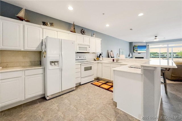 kitchen featuring white appliances, backsplash, a sink, a peninsula, and a kitchen breakfast bar