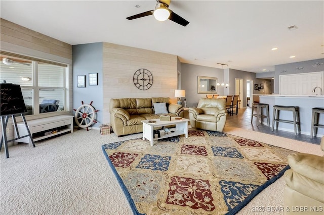 carpeted living area with recessed lighting, a ceiling fan, and wooden walls