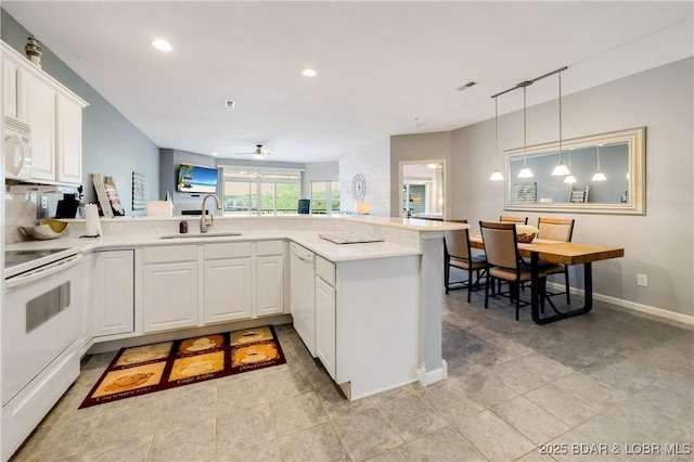 kitchen featuring a sink, light countertops, recessed lighting, white appliances, and a peninsula