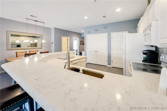 kitchen with white microwave, visible vents, light stone counters, white cabinetry, and electric range