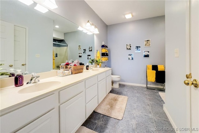 full bath featuring toilet, a stall shower, double vanity, and a sink