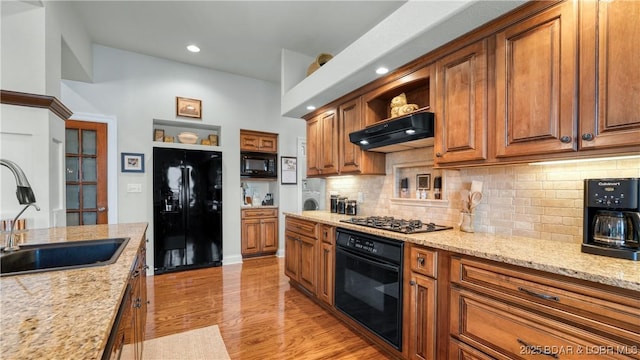 kitchen featuring open shelves, decorative backsplash, under cabinet range hood, a sink, and black appliances