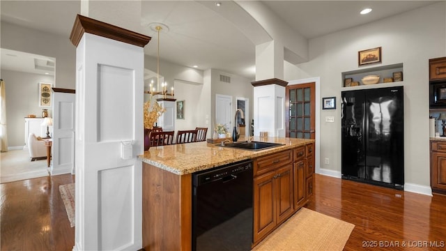 kitchen with brown cabinets, a sink, visible vents, dark wood-style floors, and black appliances