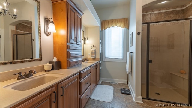 bathroom featuring double vanity, a sink, baseboards, and a stall shower