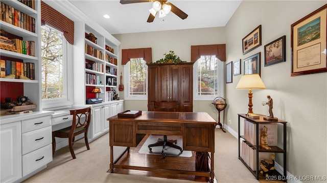 office with ceiling fan, built in desk, and light colored carpet