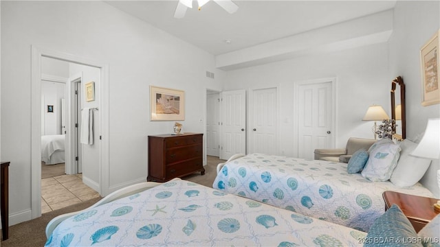 tiled bedroom with ceiling fan, carpet, two closets, baseboards, and visible vents