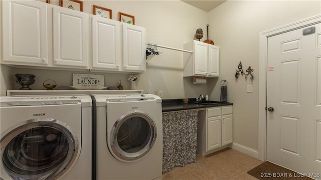 washroom featuring washing machine and dryer, baseboards, a sink, cabinet space, and light tile patterned floors