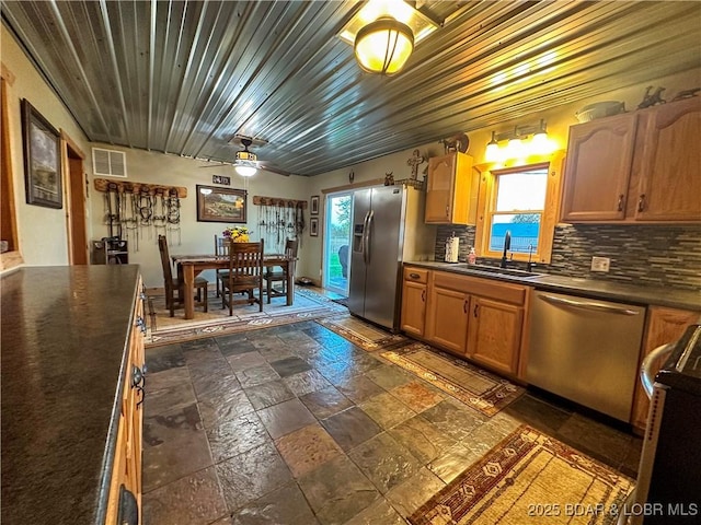 69985 US Highway 50, Tipton, MO 65081 - kitchen featuring a sink, appliances with stainless steel finishes, dark countertops, stone tile floors, and decorative backsplash
