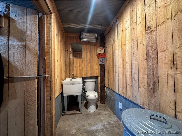 69985 US Highway 50, Tipton, MO 65081 - half bath with toilet, wooden walls, concrete flooring, and a sink