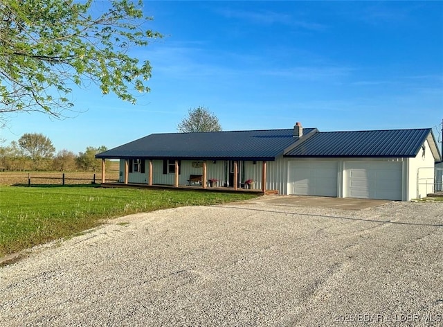 69985 US Highway 50, Tipton, MO 65081 - view of front of house featuring driveway, an attached garage, metal roof, covered porch, and a chimney