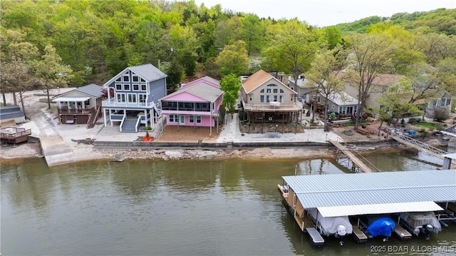 view of dock with stairs, a deck with water view, and a view of trees