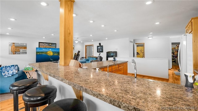 kitchen featuring a kitchen bar, light wood-type flooring, recessed lighting, and freestanding refrigerator