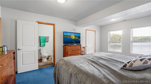 bedroom with connected bathroom, visible vents, and dark colored carpet