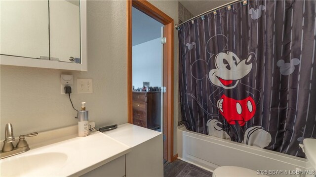 bathroom featuring toilet, wood finished floors, shower / tub combo, and vanity