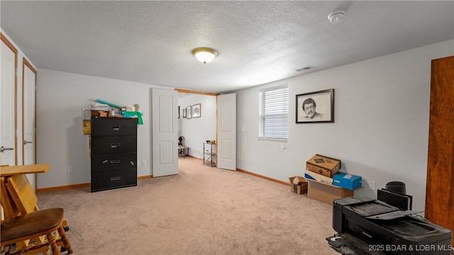 sitting room with a textured ceiling, visible vents, light colored carpet, and baseboards