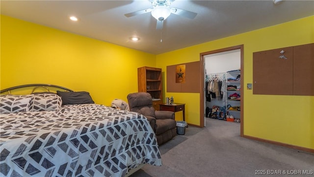 bedroom with carpet floors, a closet, baseboards, a ceiling fan, and a walk in closet