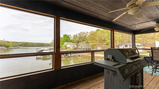 sunroom featuring a ceiling fan and a water view