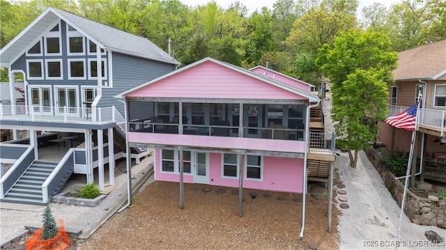 back of property featuring stairway and a sunroom